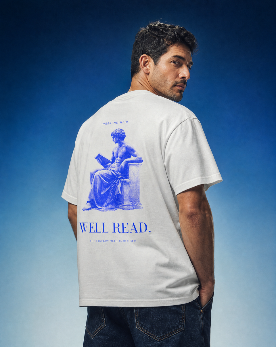 White | Lifestyle | Studio portrait on a blue backdrop, man looking over his shoulder in the Well Read Tee in White, back print showing